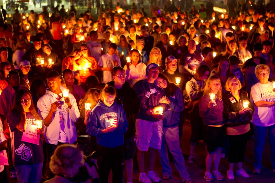 Lots of people gather with candles for Luminaria, purple glow at the front of the crowd