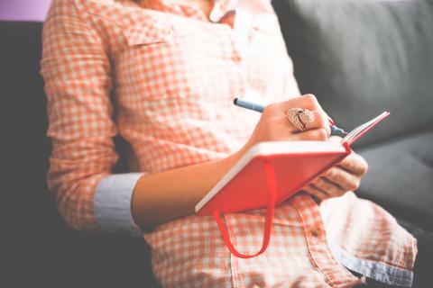 woman jotting down notes in a notebook